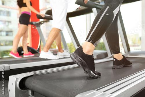 Legs of sporty woman running on treadmill in gym, close up view