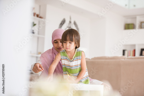 Arabic mother with little son learning in living room