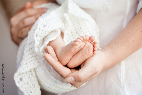 Baby feet in mother hands. Tiny Newborn Baby's feet on female Sh photo