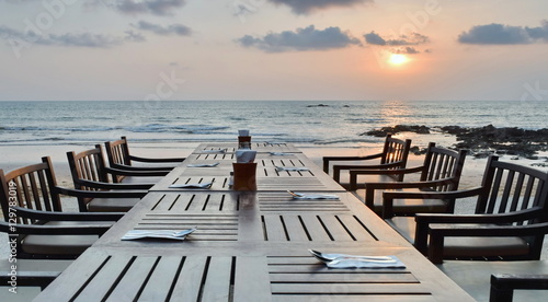 Diner table set on the beach at sunset time.