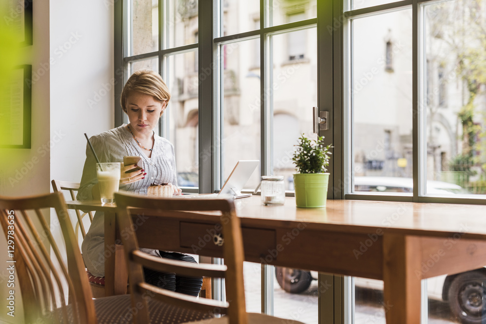 Young woman with cell phone and tablet in a cafe Young woman with cell phone and tablet in a cafe
