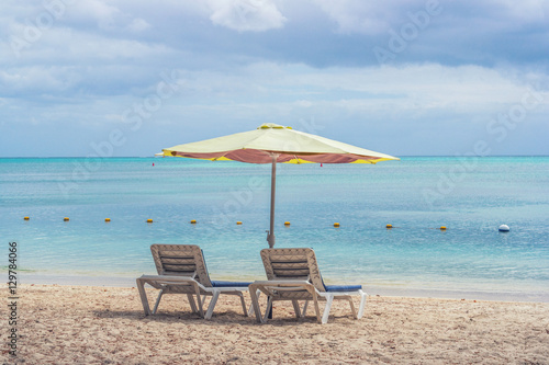 Two lounge chairs with sun umbrella on a beach © Alexey Pelikh