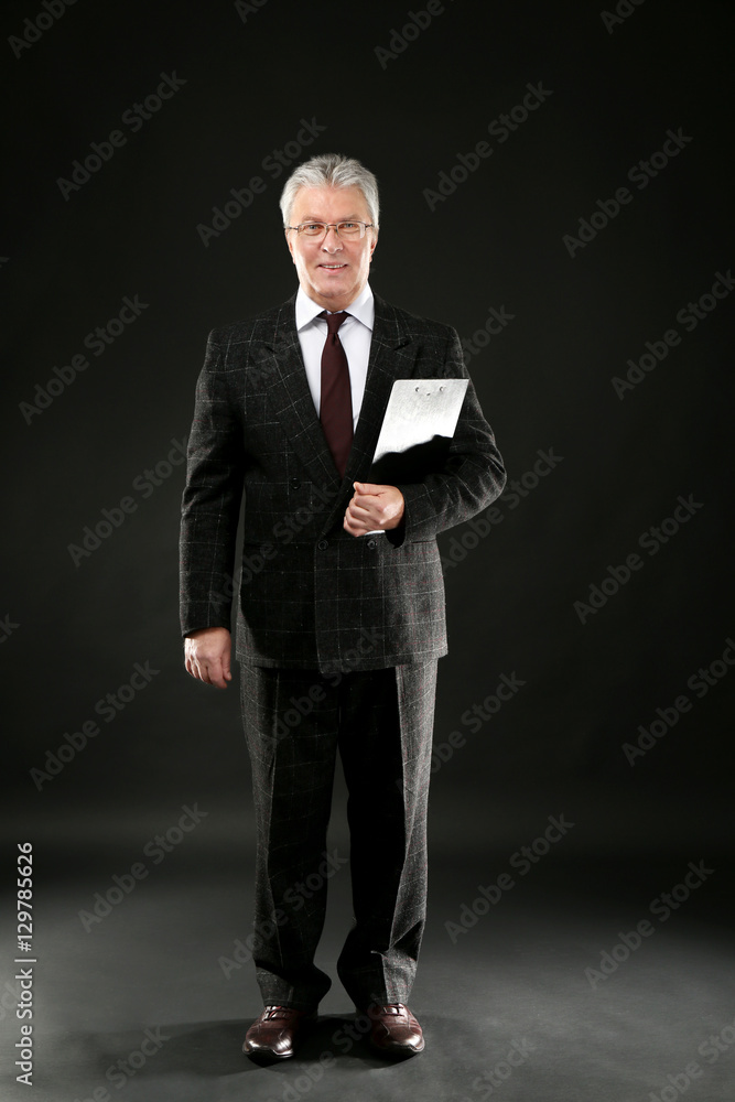 Senior businessman with clipboard on black background Senior businessman with clipboard on black background