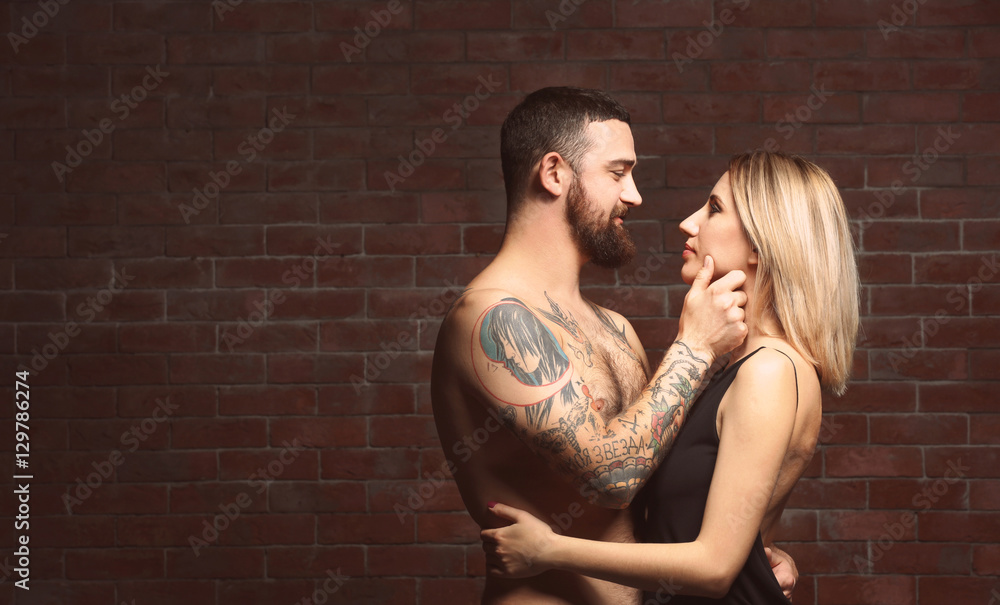 Fashion tattooed couple on brick wall background Fashion tattooed couple on brick wall background