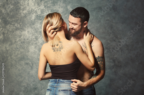 Passion tattooed beautiful couple on gray wall background © Africa Studio