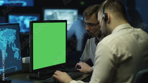 Concentrated Programmers Work on Personal Computers Located in a System Control Room. Computer has Green Screen. Shot on RED Cinema Camera in 4K (UHD). photo