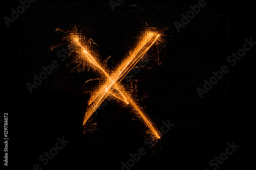 Letter X made of sparklers on black
