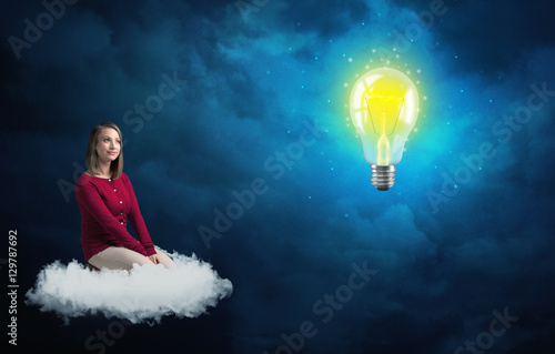 Woman sitting on a cloud lokking at huge lightbulb