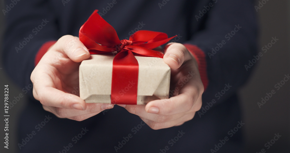female teen hands show craft paper gift box with red bow, shallow focus female teen hands show craft paper gift box with red bow, shallow focus