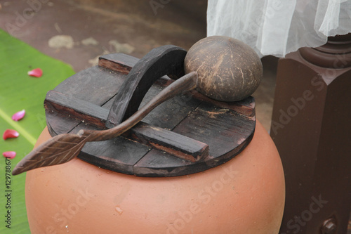 Thai pot contain water with the lid and coconut shell spetula. photo