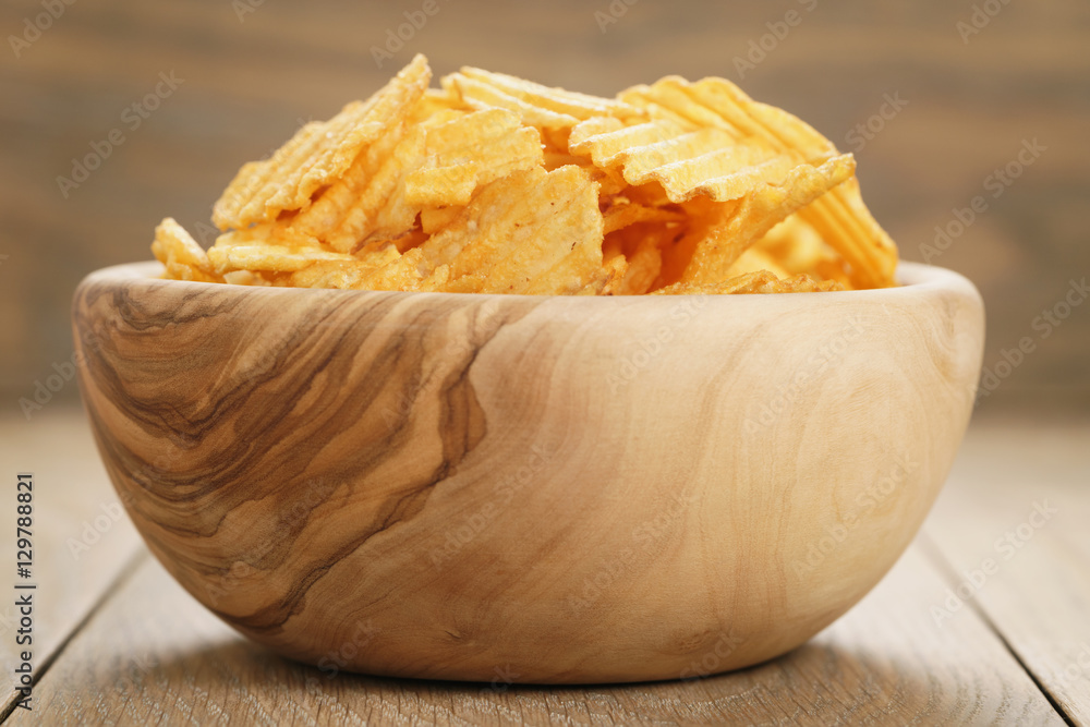 rippled potato chips with paprika flavour in wooden bowl, closeup photo rippled potato chips with paprika flavour in wooden bowl, closeup photo