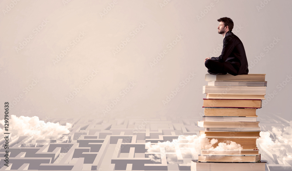 Businessman sitting on books in labirynth Businessman sitting on books in labirynth
