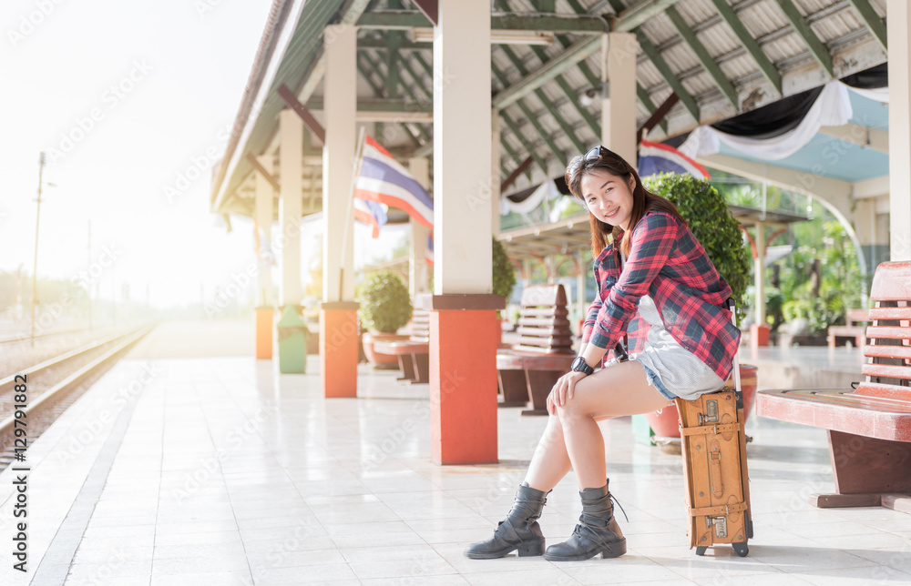 Hipster girl setting on leather vintage bag at railway station, concept travel and leisure