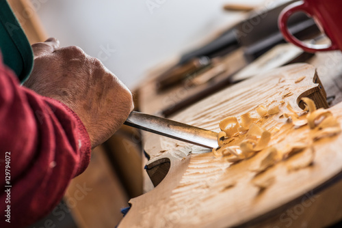violin maker carving with a chisel on a violin body