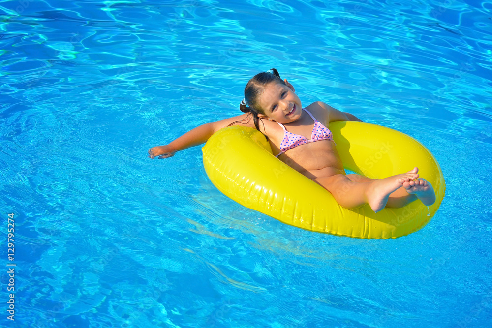 Real toddler girl relaxing at swimming pool