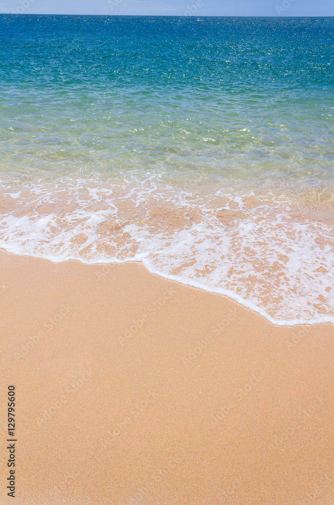 Strandsand im Sommer mit türkis-blauem Wasser.