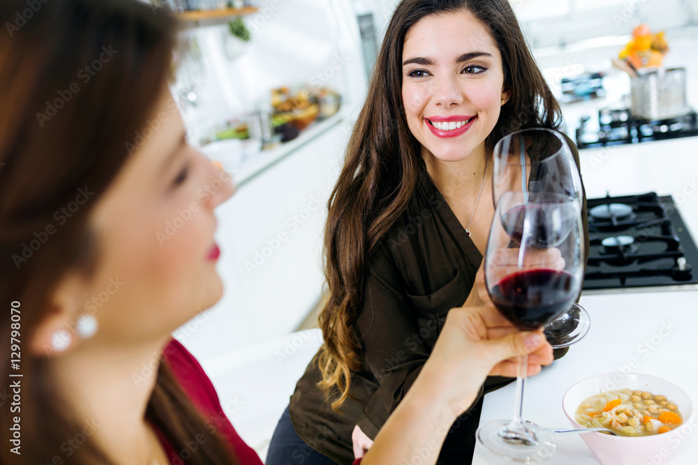 Two beautiful young women drinking some wine while eating in the kitchen. Two beautiful young women drinking some wine while eating in the kitchen.