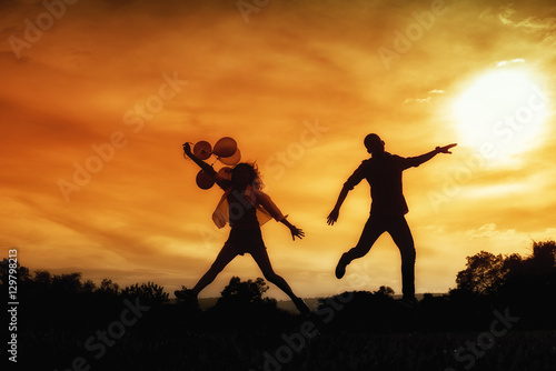 Silhouette of happy lovers jumping against sunset. light and sha