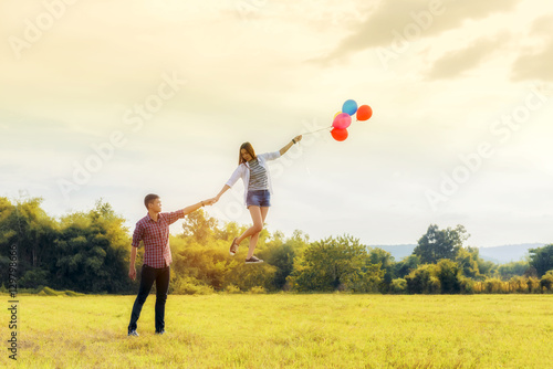Levitating woman with colorful balloon and with holding hand gir