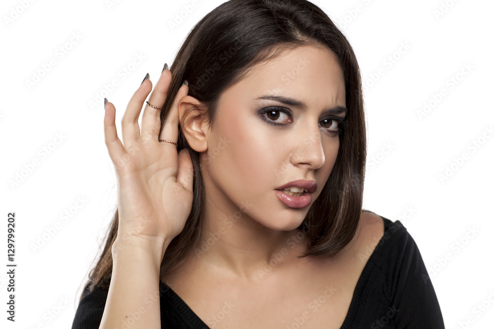 beautiful young woman holds the hand behind the ear to better hear beautiful young woman holds the hand behind the ear to better hear