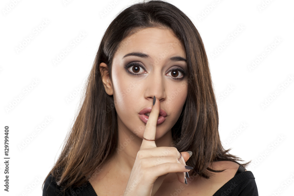 beautiful young woman with a finger in front of her lips. concept for silence beautiful young woman with a finger in front of her lips. concept for silence