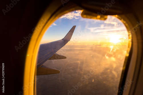 Wing of the air plane on the sea of clouds sunset sky background