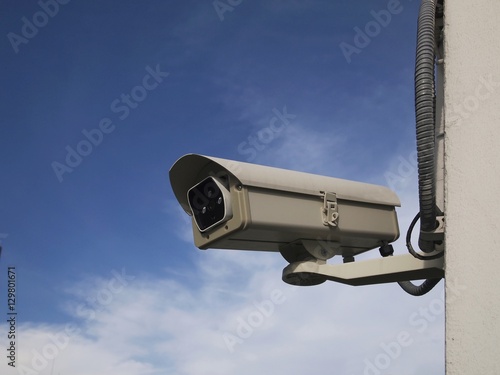 CCTV  security camera against cloudy blue sky
