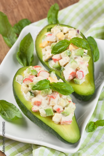 Avocado salad / Avocado stuffed with crab, cucumber, egg, red onion and sauce mayonnaise on white plate