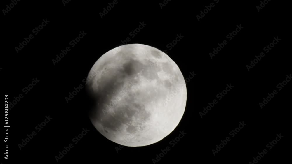 Full moon passing in front of small branch on dark night Full moon passing in front of small branch on dark night