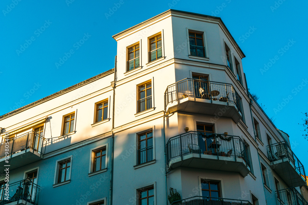 Naklejka premium white facaded corner house in warm sunlight