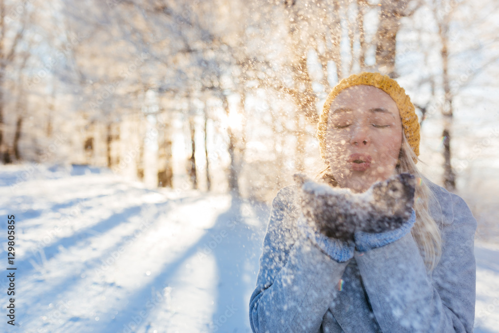 © Myvisuals - Young woman blowing snowflakes from hands. Selective focus