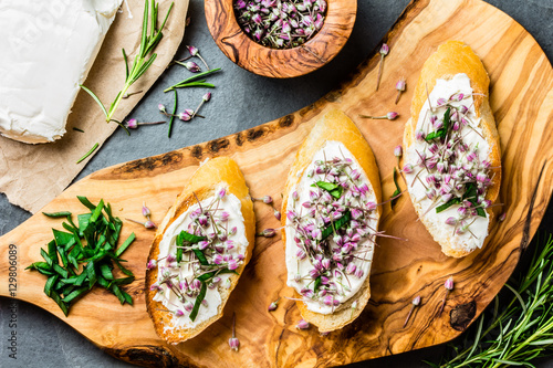 Fotografia Sandwiches with cream cheese and garlic edible flowers, olive board