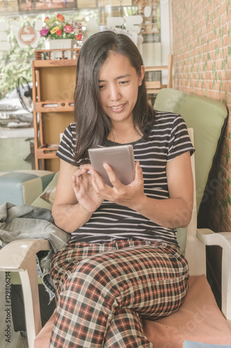 Beautiful asian woman using tablet at cafe while drinking coffee, Relaxing concept.