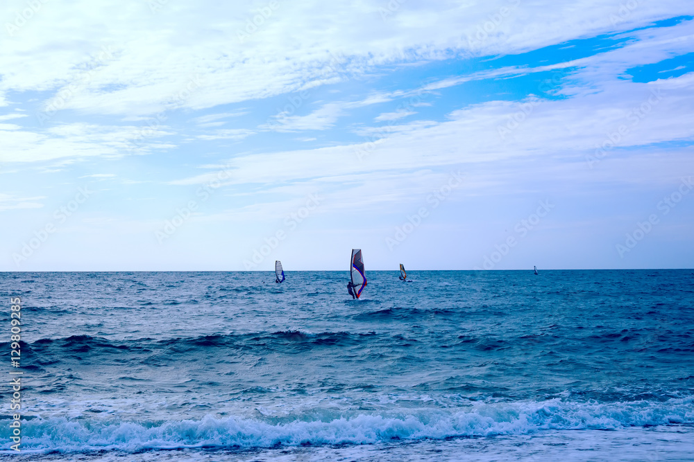 Group of windsurfers on boards in wavy sea Group of windsurfers on boards in wavy sea
