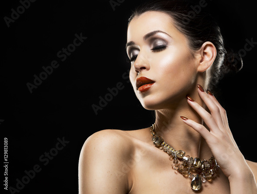 beautiful brunette with dark makeup wearing gold jewellery