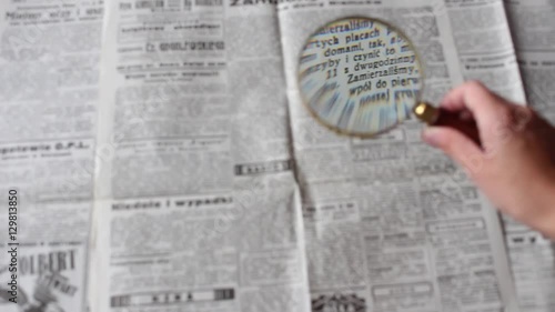 reading the newspaper through a magnifying glass