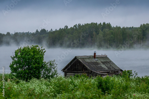 Tablou canvas The traditional Russian log hut in poor condition on the river bank
