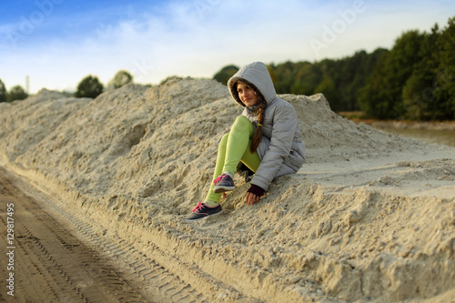 Dziewczynka siedzi na piachu.