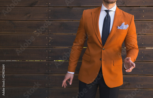 Fototapeta Male model in a suit posing in front of a wooden wall