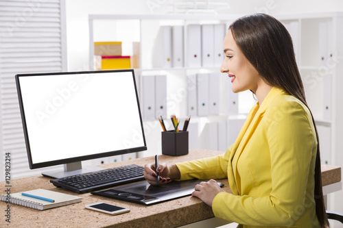 Woman in a yellow jacket drawing at her computer
