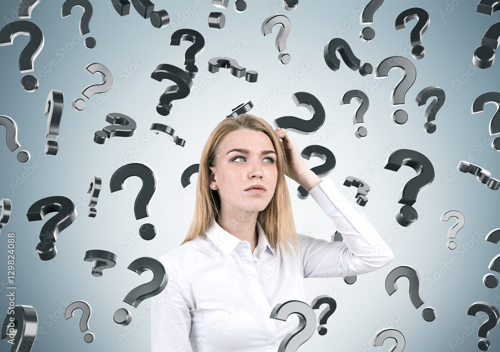 Blond woman and question marks on gray wall Blond woman and question marks on gray wall