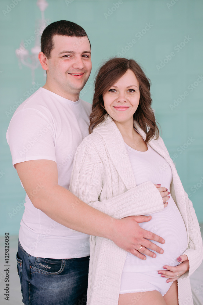 Family waiting for baby's birth. A pregnant woman and her husband wearing white clothing Family waiting for baby's birth. A pregnant woman and her husband wearing white clothing
