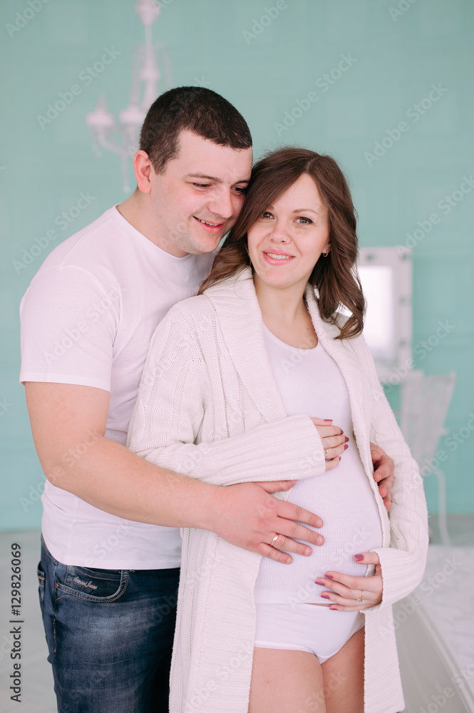 Family waiting for baby's birth. A pregnant woman and her husband wearing white clothing Family waiting for baby's birth. A pregnant woman and her husband wearing white clothing