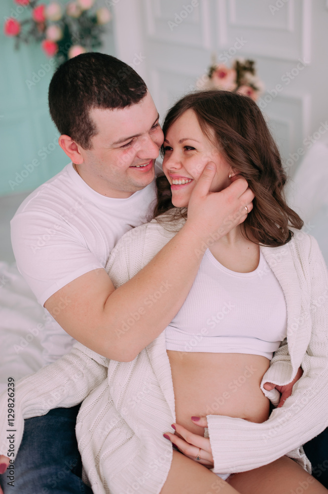Family waiting for baby's birth. A pregnant woman and her husband wearing white clothing Family waiting for baby's birth. A pregnant woman and her husband wearing white clothing