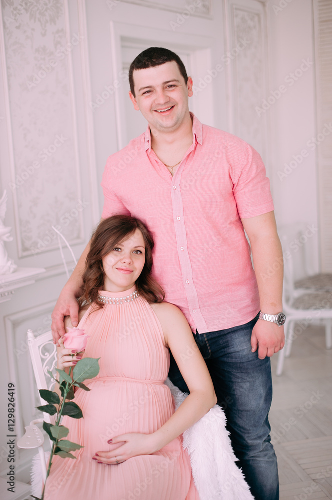 Family waiting for baby's birth. A pregnant woman and her husband wearing white clothing Family waiting for baby's birth. A pregnant woman and her husband wearing white clothing