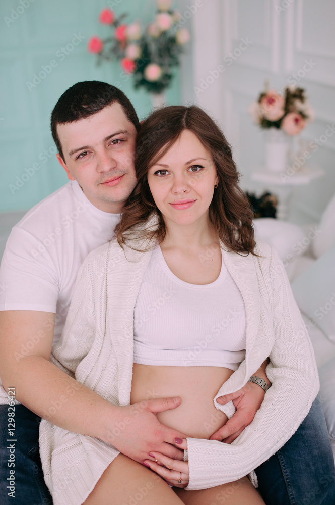 Family waiting for baby's birth. A pregnant woman and her husband wearing white clothing Family waiting for baby's birth. A pregnant woman and her husband wearing white clothing