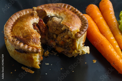 Savoury pie served with glazed carrots and mushy peas.