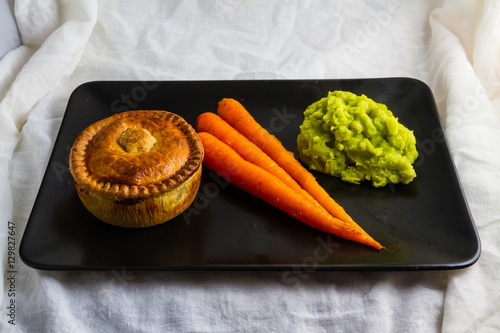 Fotografia Savoury pie served with glazed carrots and mushy peas.