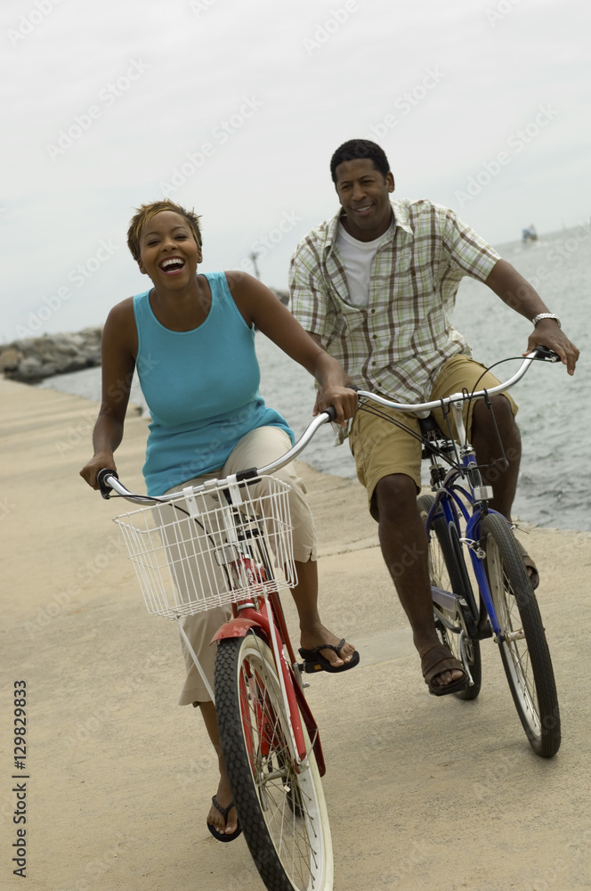 Obraz premium Portrait of a happy African American couple cycling on the beach