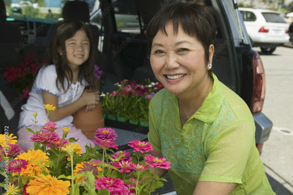 Portrait of happy grandmother loading various flowers in car